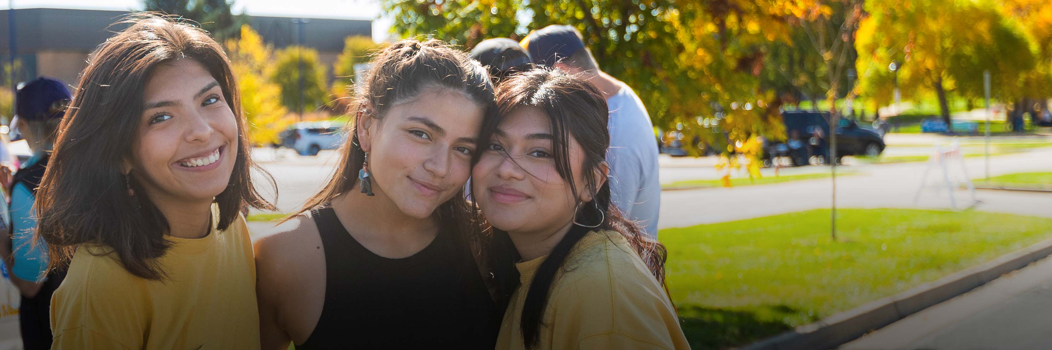 3 latina 学生 smiling during an event.